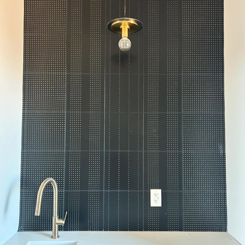Dark green glazed tile in a fine vertical stack, lit from one side.