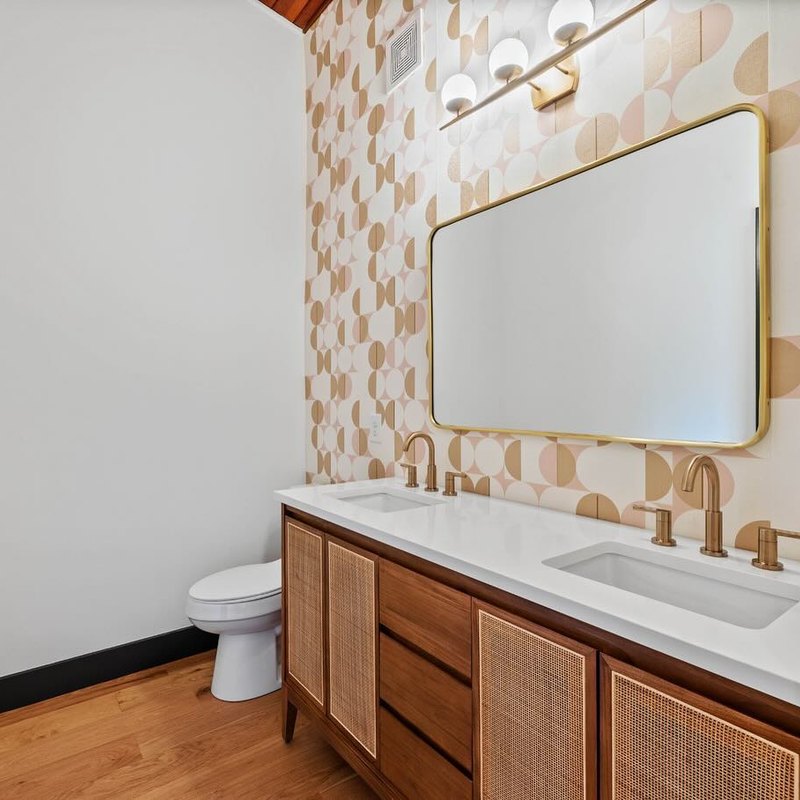 Cream scalloped tile wall behind a caned vanity and an arched mirror.