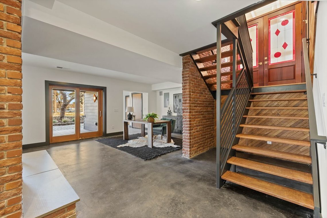 Open stair in blackened steel and timber treads set against an exposed brick wall.